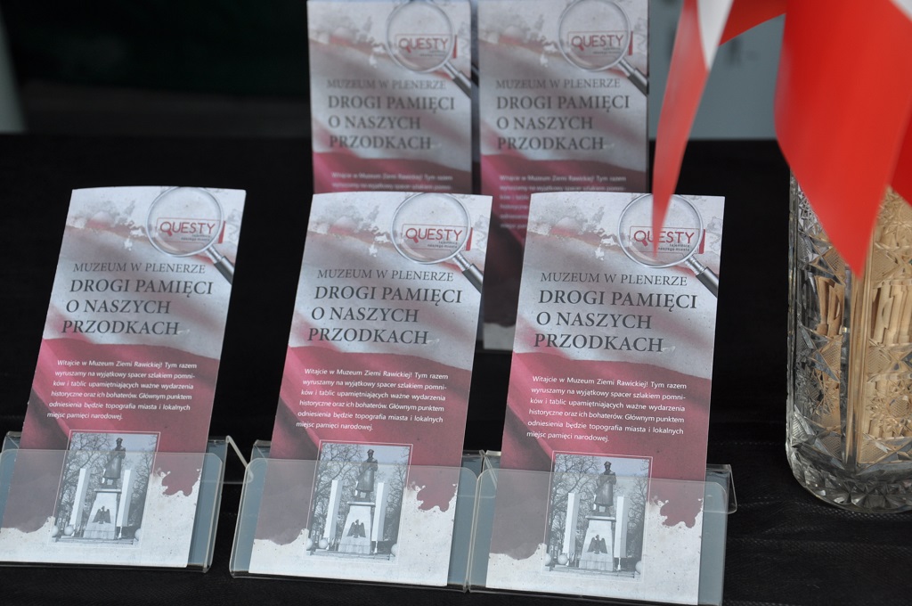 W ramach tegorocznych lokalnych obchod&oacute;w Narodowego Święta Niepodległości Muzeum Ziemi Rawickiej zaprosiło mieszkańc&oacute;w oraz turyst&oacute;w odwiedzających Rawicz do udziału w specjalnym wydarzeniu kulturalno-edukacyjnym. 11 listopada odbyła się premiera kolejnego muzealnego questu pt. &bdquo;Drogi pamięci o naszych przodkach&rdquo;.  Na czynnym w tym dniu muzealnym stoisku promocyjnym uczestnicy zabawy otrzymywali karty zadań z opisem &bdquo;szlaku rawickich miejsc pamięci narodowej&rdquo; oraz zagadkami, kt&oacute;rych rozwiązanie było możliwe tylko w ramach przejścia całej trasy i obejrzenia wskazanych w treści questu obiekt&oacute;w historycznych. Stoisko zostało zaaranżowane tematycznie &ndash; przed ratuszem stanęła budka polskiego strażnika oraz szlaban graniczny, przypominające o tym, że po odzyskaniu niepodległości zaledwie kilka kilometr&oacute;w od Rawicza była wytyczona polsko-niemiecka granica państwowa. Na zwiedzających w muzeum czekał wyjątkowy przewodnik &ndash; sam marszałek Piłsudski w galowym mundurze. W rolę bohatera narodowego wcielił się jeden z pracownik&oacute;w muzeum.  Na &bdquo;szlak miejsc pamięci&rdquo; wyruszyło kilkadziesiąt os&oacute;b, zar&oacute;wno pieszo, jak i rowerami. Ponad dwadzieścia drużyn rodzinnych prawidłowo rozwiązało questowe hasło, otrzymując na zakończenie muzealną pieczęć oraz upominki związane z obchodami Święta Niepodległości. Rodziny z dziećmi spotkały się także w ratuszu na międzypokoleniowych muzealnych warsztatach manualnych, kt&oacute;rych tematem r&oacute;wnież były barwy i symbole narodowe. Uczestnicy warsztat&oacute;w wykonywali tym razem ekologiczne przestrzenne mapy Polski. 